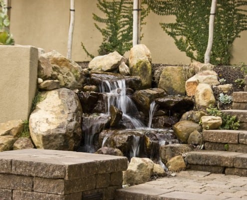 Pondless stone waterfall next to paving stone steps