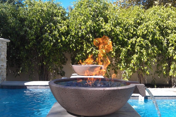 Fire Bowls on top of Fountains Pouring Water into a Pool