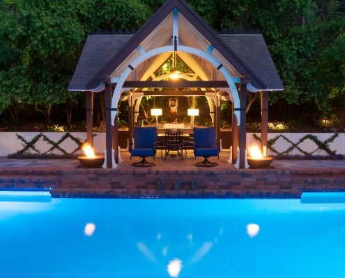 Pool with paving stone pool deck, cabana and fire pits